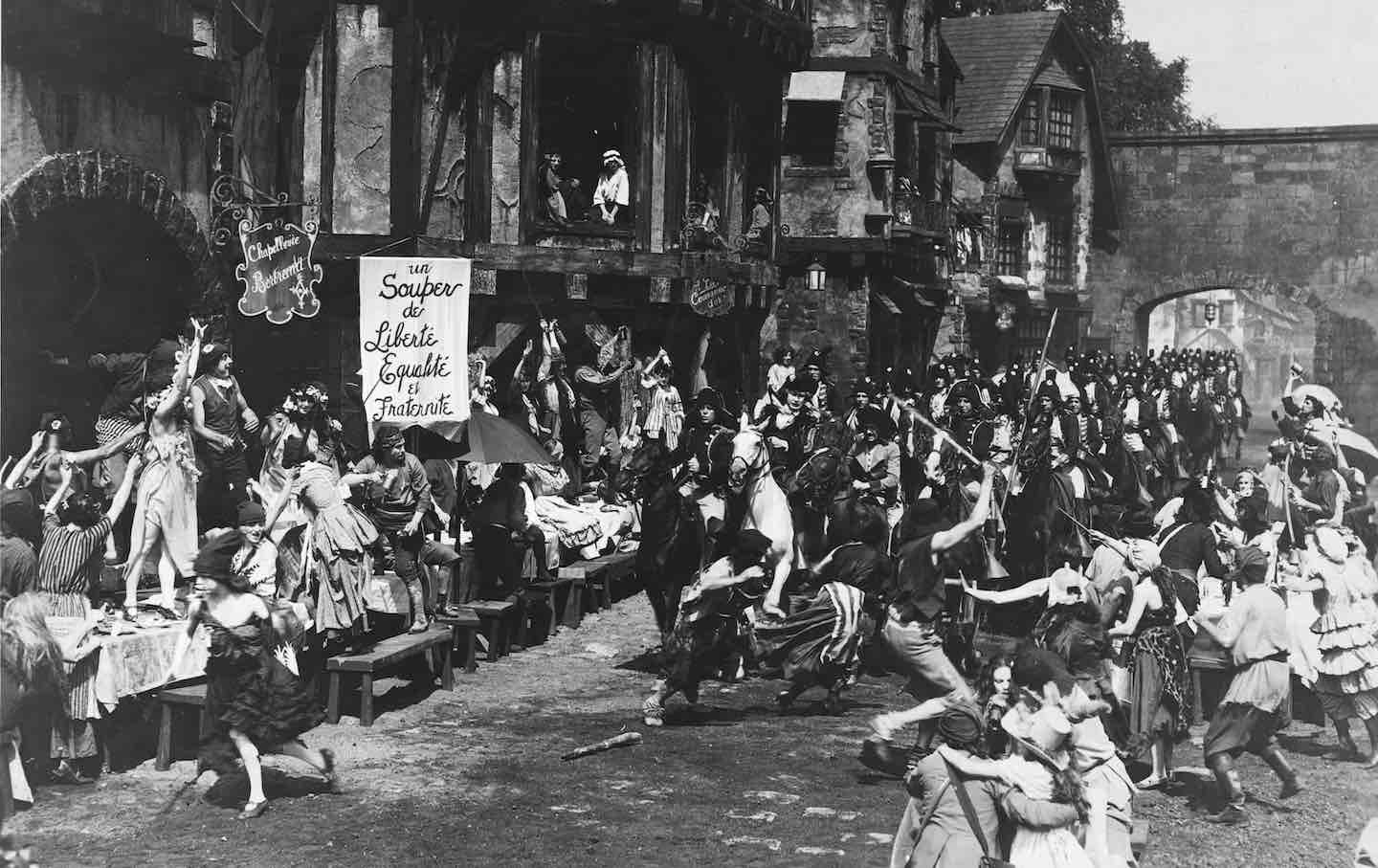 A scene from the film “Orphans of the Storm” depicting a group carrying a sign bearing the slogan “Liberté, Egalité et Fraternité,” 1921.