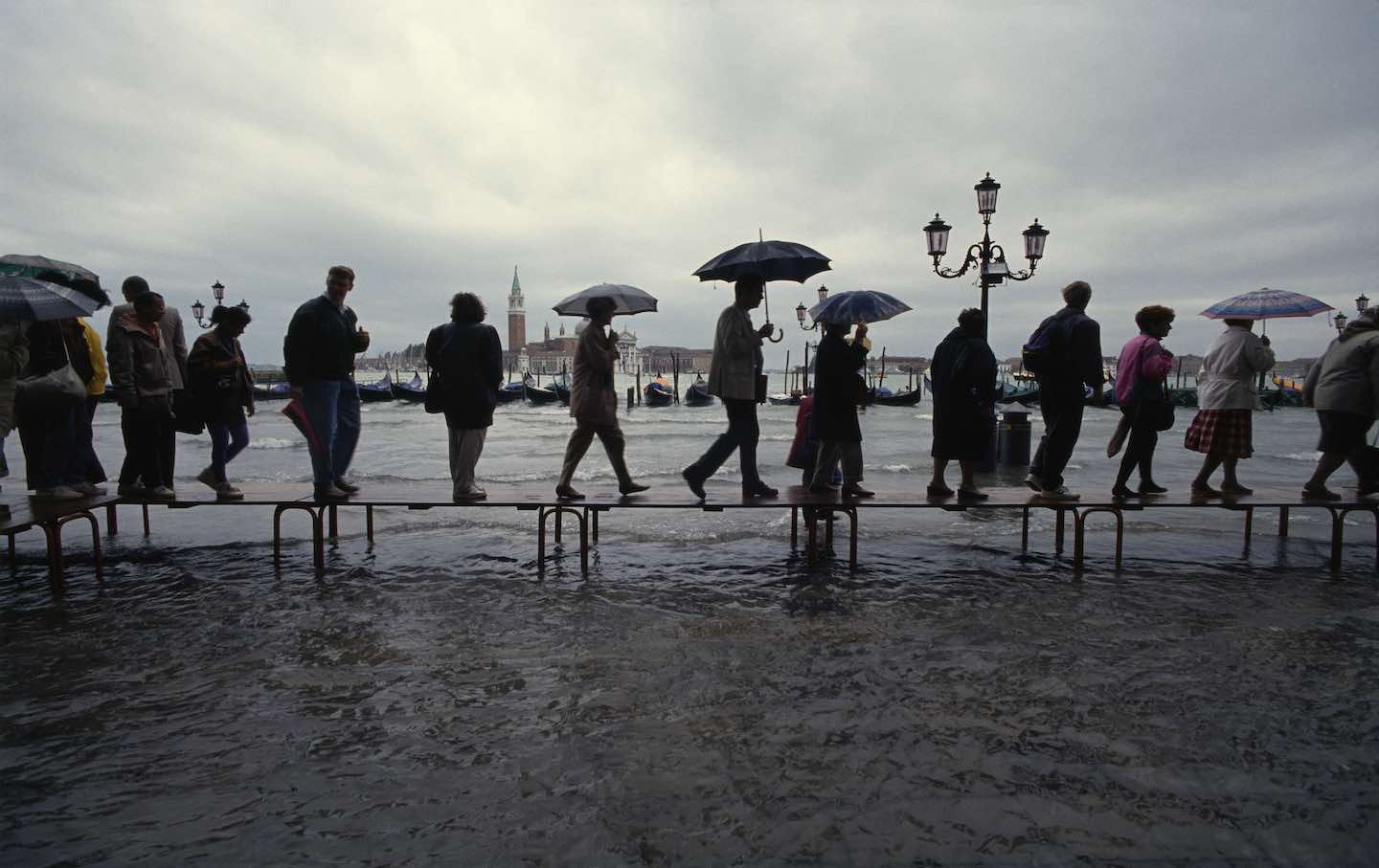 Locals and tourists walk on gangplanks through the flooded city center of Venice.