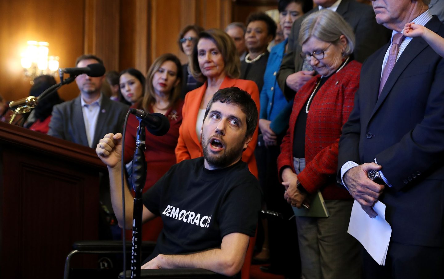 Ady Barkan (C) delivers remarks during a rally organized by House minority leader Nancy Pelosi (D-Calif.) at the US Capitol,December 19, 2017.