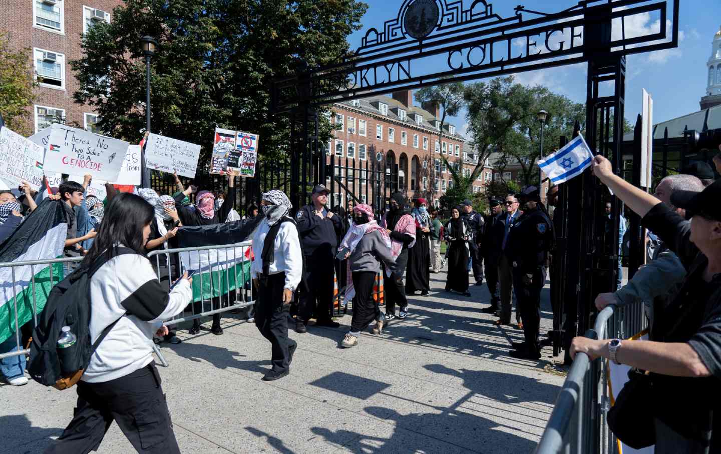 Protestors stand behind barricades at the gates of Brooklyn College