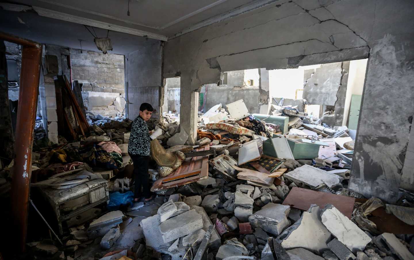 A boy searches through buildings, destroyed during Israeli air raids in the southern Gaza Strip on November 10, 2023, in Khan Yunis, Gaza.