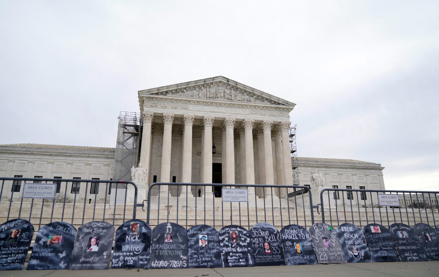 Headstones bearing information about people who died from using OxyContin line a security fence outside the Supreme Court Building on Monday, December 4, 2023.