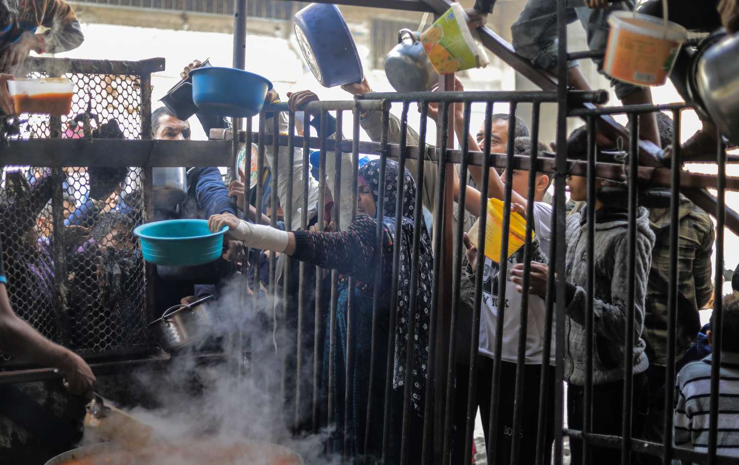 Palestinians gather to collect food cooked by volunteers for people who evacuated from Khan Yunis to Rafah