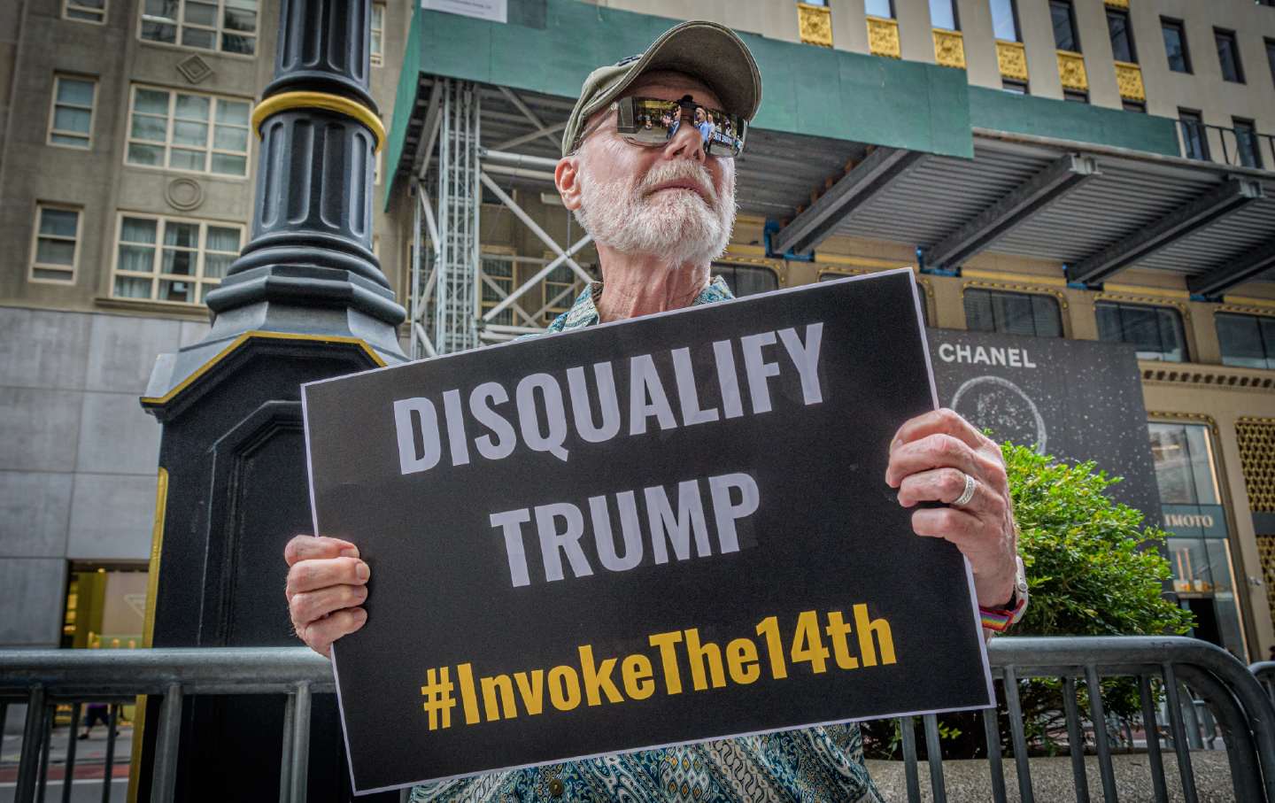 A protester stands outside Trump Tower in Manhattan demanding that state governments disqualify former president Trump from appearing on ballots in 2024 under the 14th Amendment.