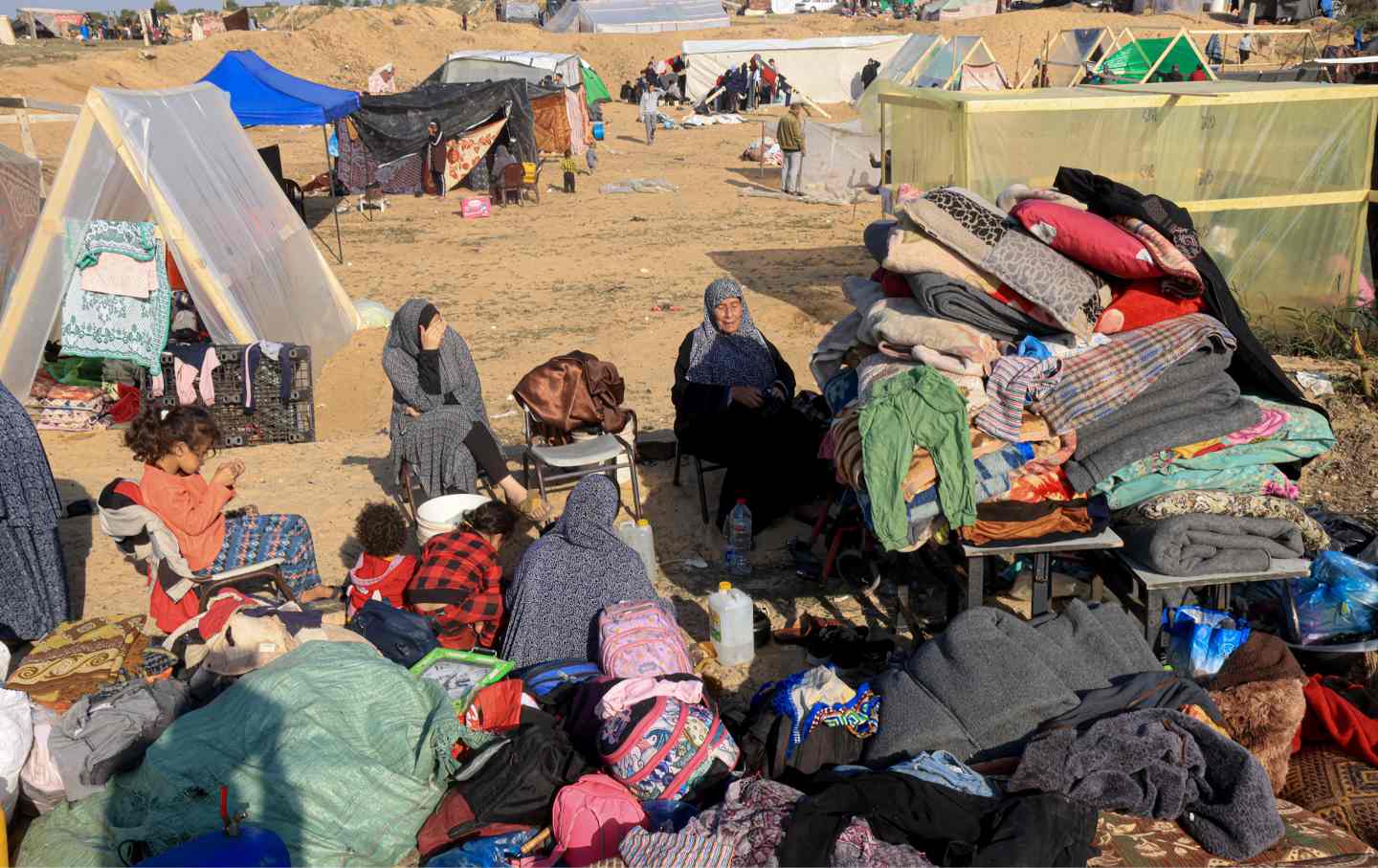 Displaced Palestinians who fled from Khan Yunis, sit with their belongings outside makeshift shelters in Rafah in the southern Gaza Strip on December 4, 2023.