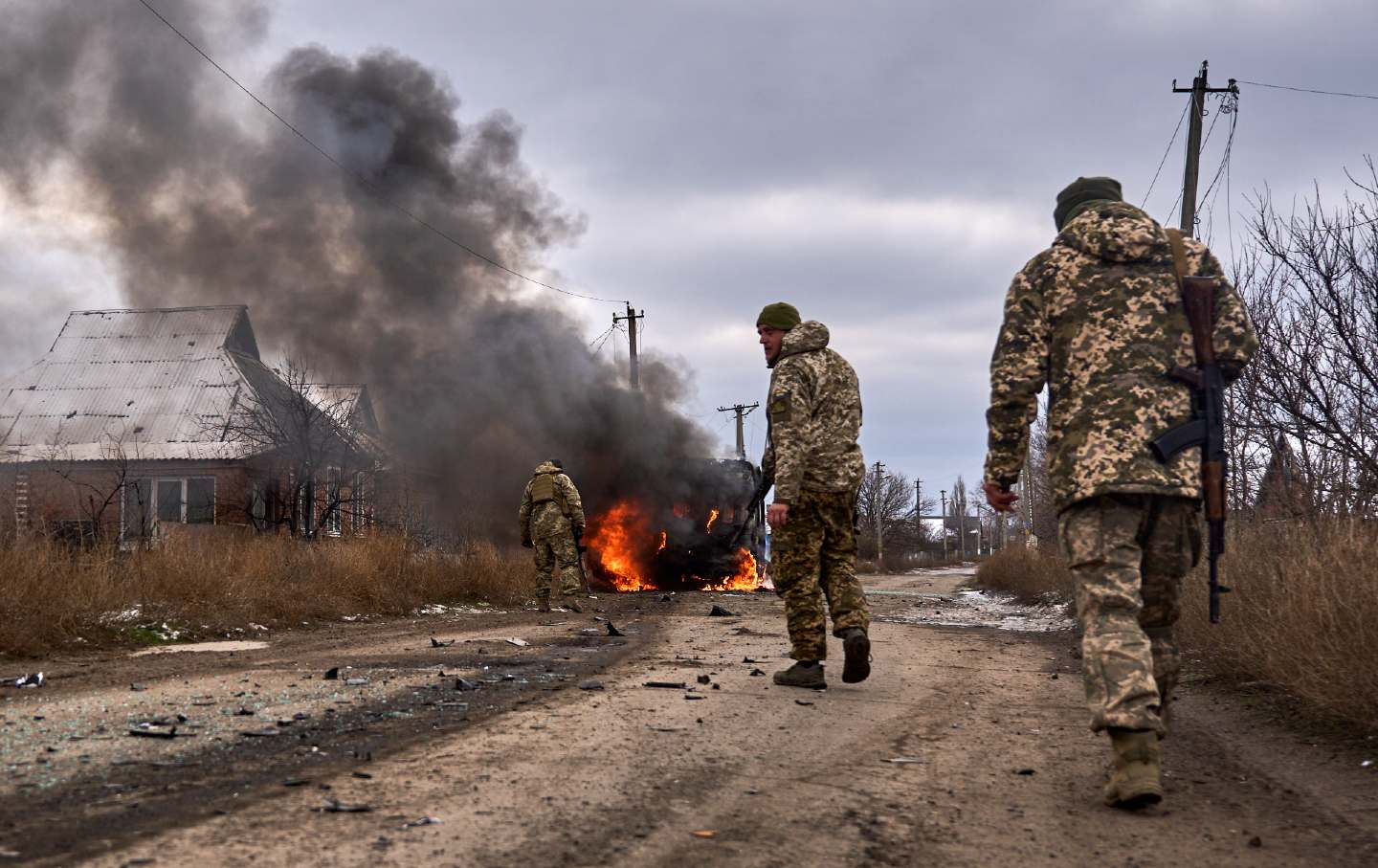 Ukrainian soldiers pass by a volunteer bus burning after a Russian drone hit it near Bakhmut, Donetsk region, Ukraine, on November 23, 2023.