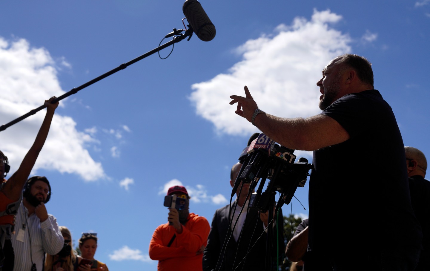 Alex Jones, shot from above in profile, gesticulating and speaking into a boom mike.