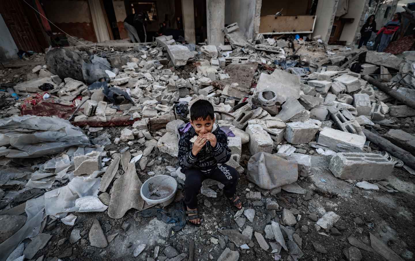 A child eats amid the rubble of destroyed buildings following Israeli bombardment in Rafah on the southern Gaza Strip on December 29, 2023, amid the ongoing battles between Israel and the Palestinian militant group Hamas.