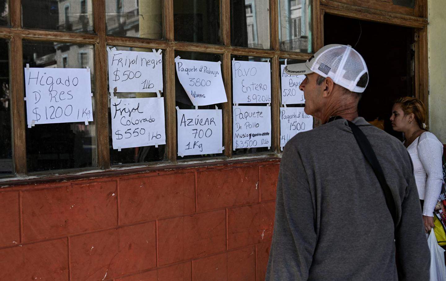 People look at food prices at a private business in Havana on December 20, 2023. Cuba's economy will shrink by up to 2 percent this year, Finance Minister Alejandro Gil estimated on Wednesday, after acknowledging that the country will not be able to achieve the projected economic growth of 3 percent by 2023.