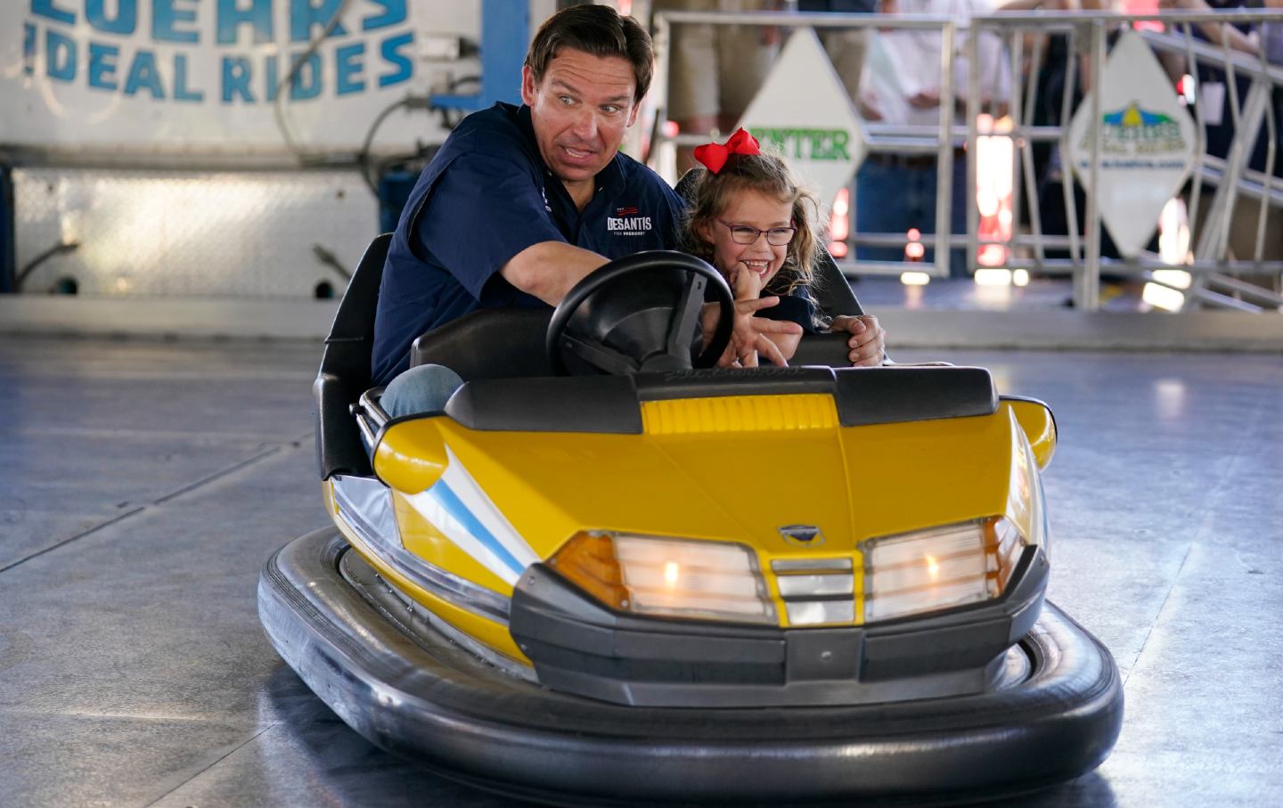 Republican presidential candidate Florida Governor Ron DeSantis drives a bumper car as his daughter Madison laughs at the Iowa State Fair on August 12, 2023, in Des Moines, Iowa
