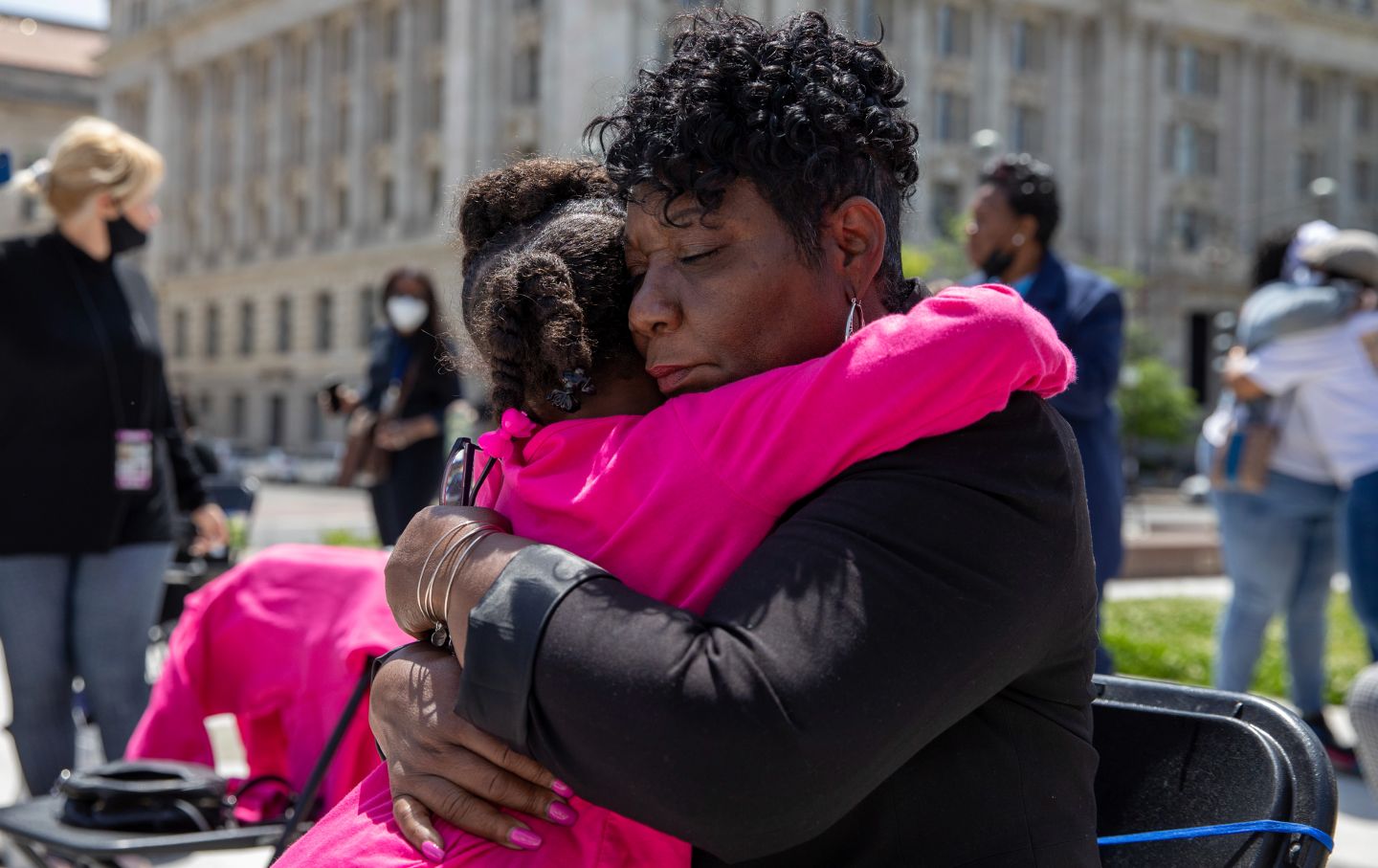 A young Black girl and an older Black woman embrace.