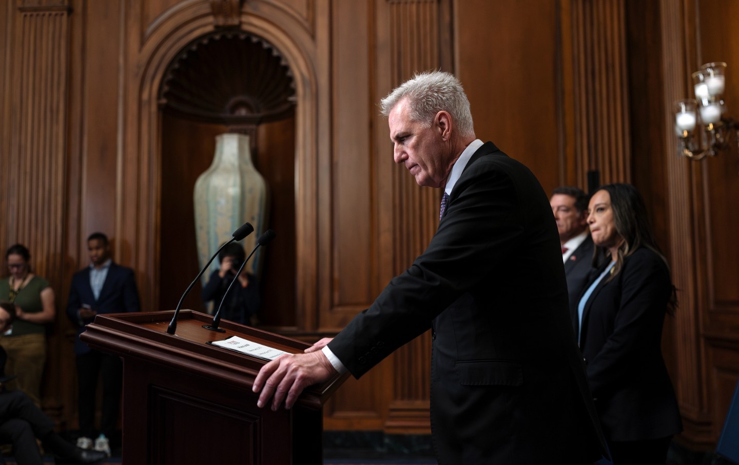 Kevin McCarthy, photographed from the side, holding a podium in the Capitol building and looking downward.