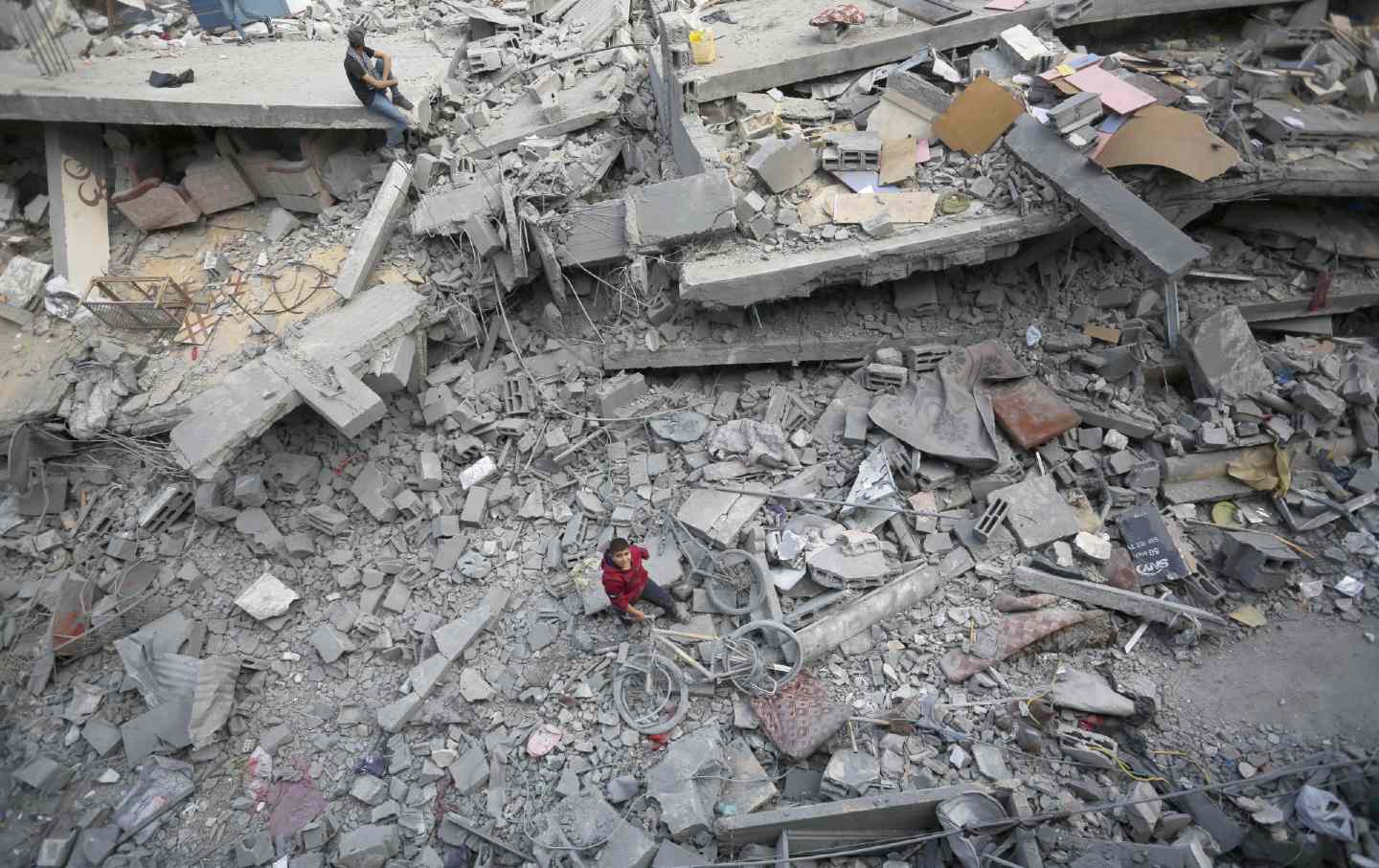 Palestinians in a destroyed residential area try to collect usable items under the rubble.