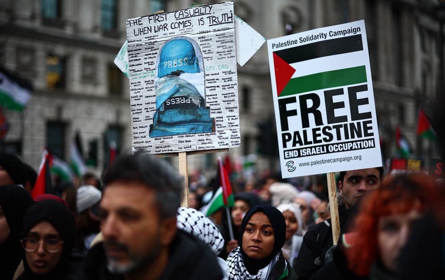 Pro-Palestinian activists and supporters carry placards, including a sign featuring names of journalists hurt during the latest conflict, during a National March for Palestine in central London on January 13, 2024.