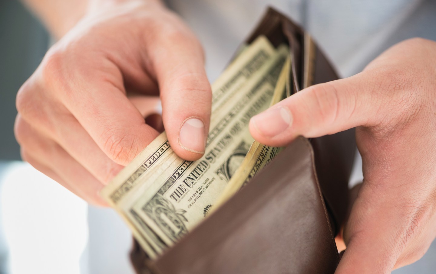 Young man holding wallet and counting money.