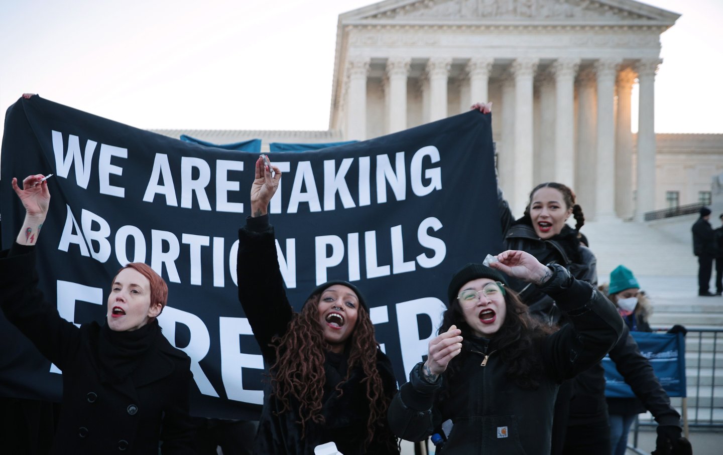 Protesters hold a huge banner reading "We Are Taking Abortion Pills Forever" in front of the Supreme Court.