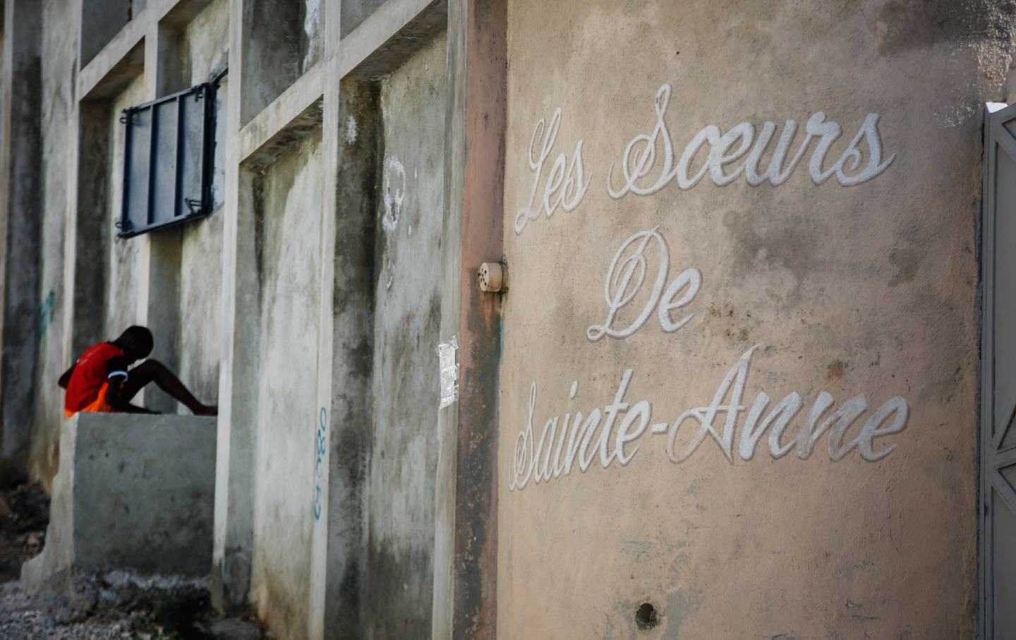 A young boy rests in front of the entrance of the Sisters of Saint-Anne residence in Port-au-Prince, Haiti.