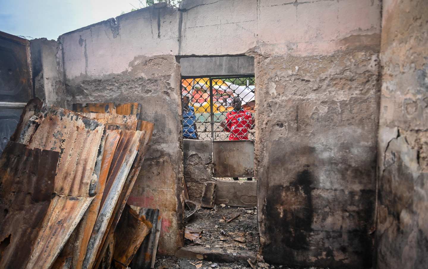 Men look through the window of a burnt-out house near Fontaine Hospital in Port-au-Prince, Haiti