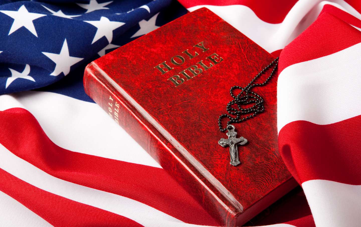 A Bible and cross lie on the American flag.