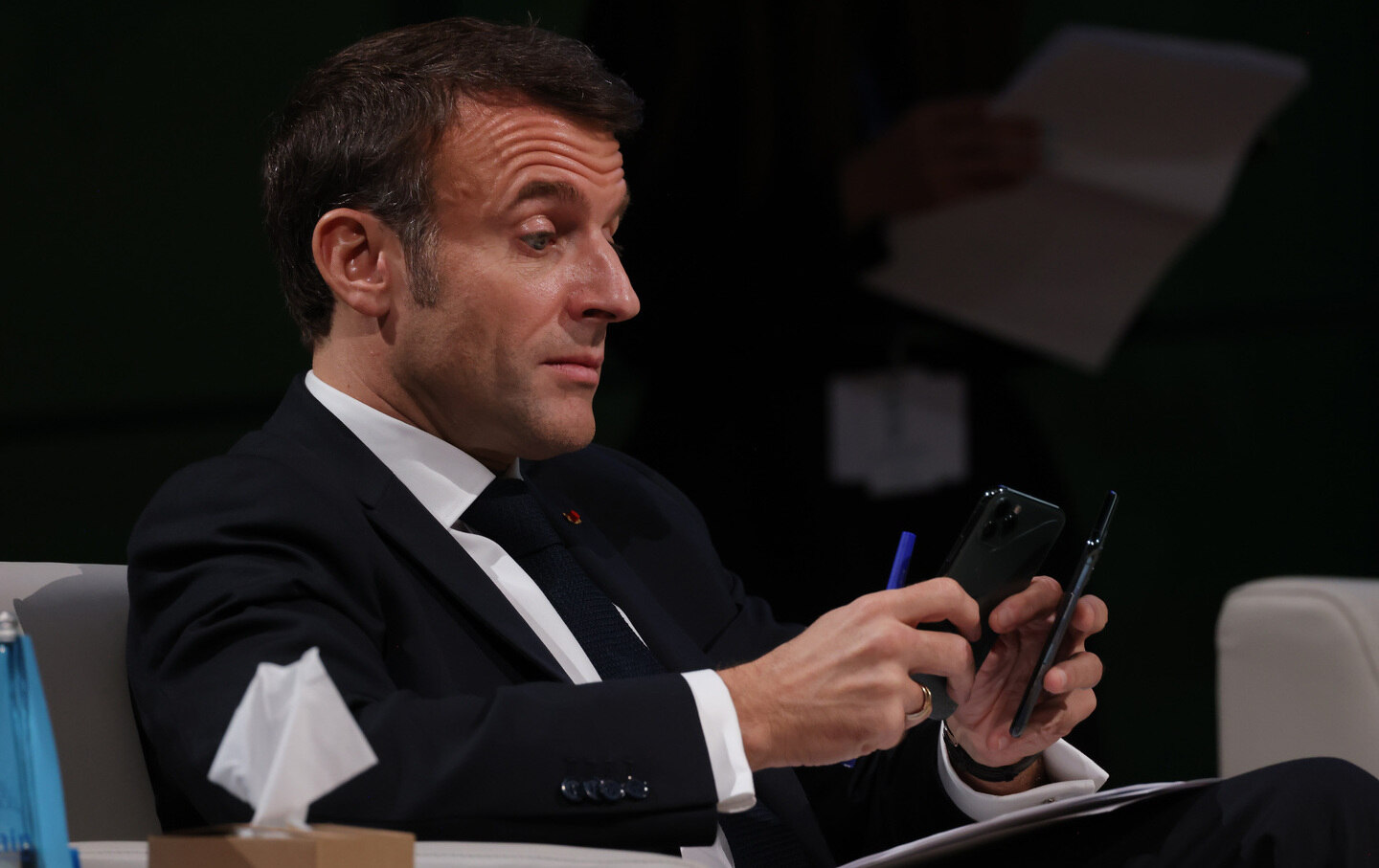 French President Emmanuel Macron looks at his smartphone.