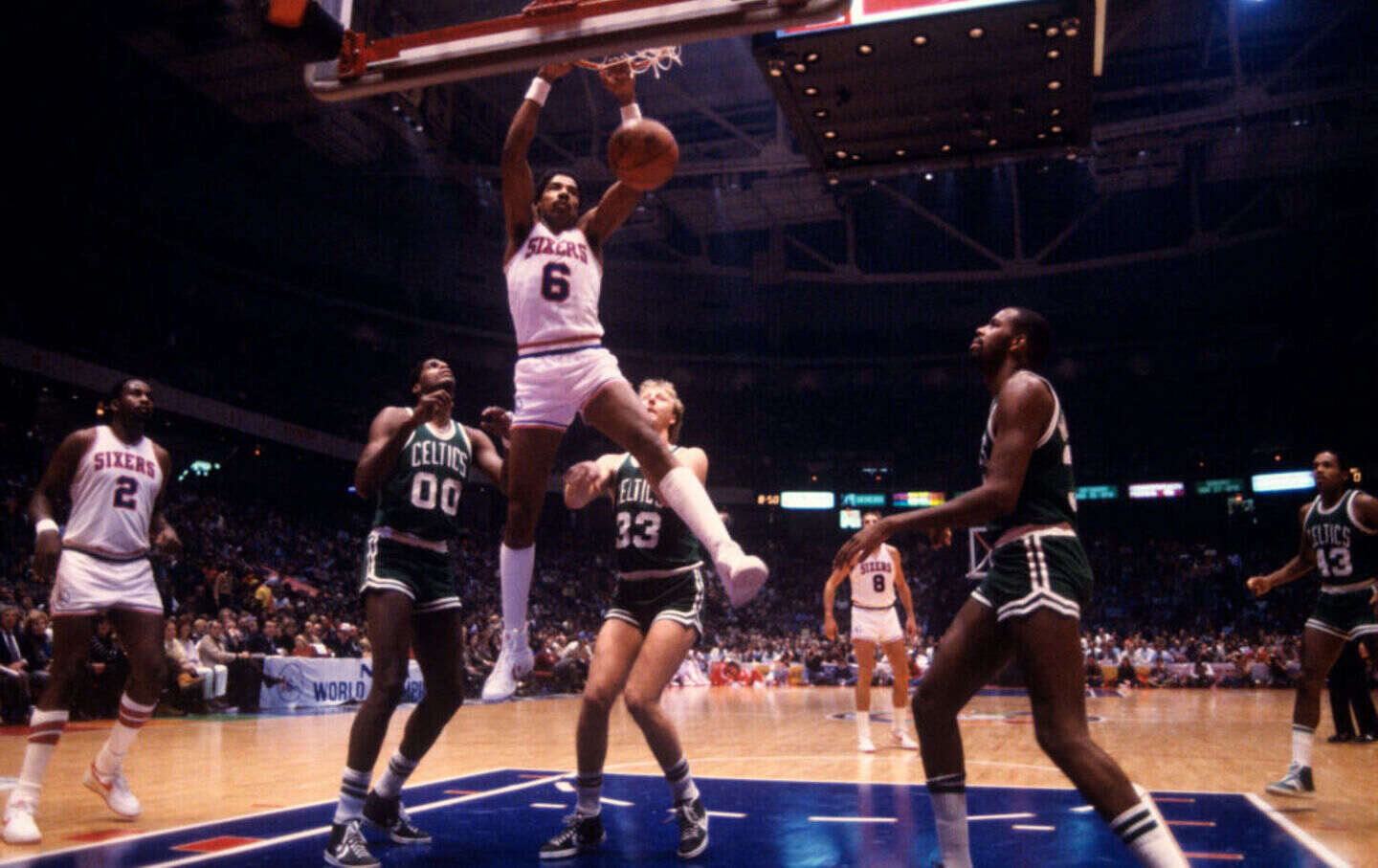 Julius Erving #6 of the Philadelphia 76ers dunks against Larry Bird #33 and Robert Parish #00 of the Boston Celtics during a game at the Spectrum in 1982.