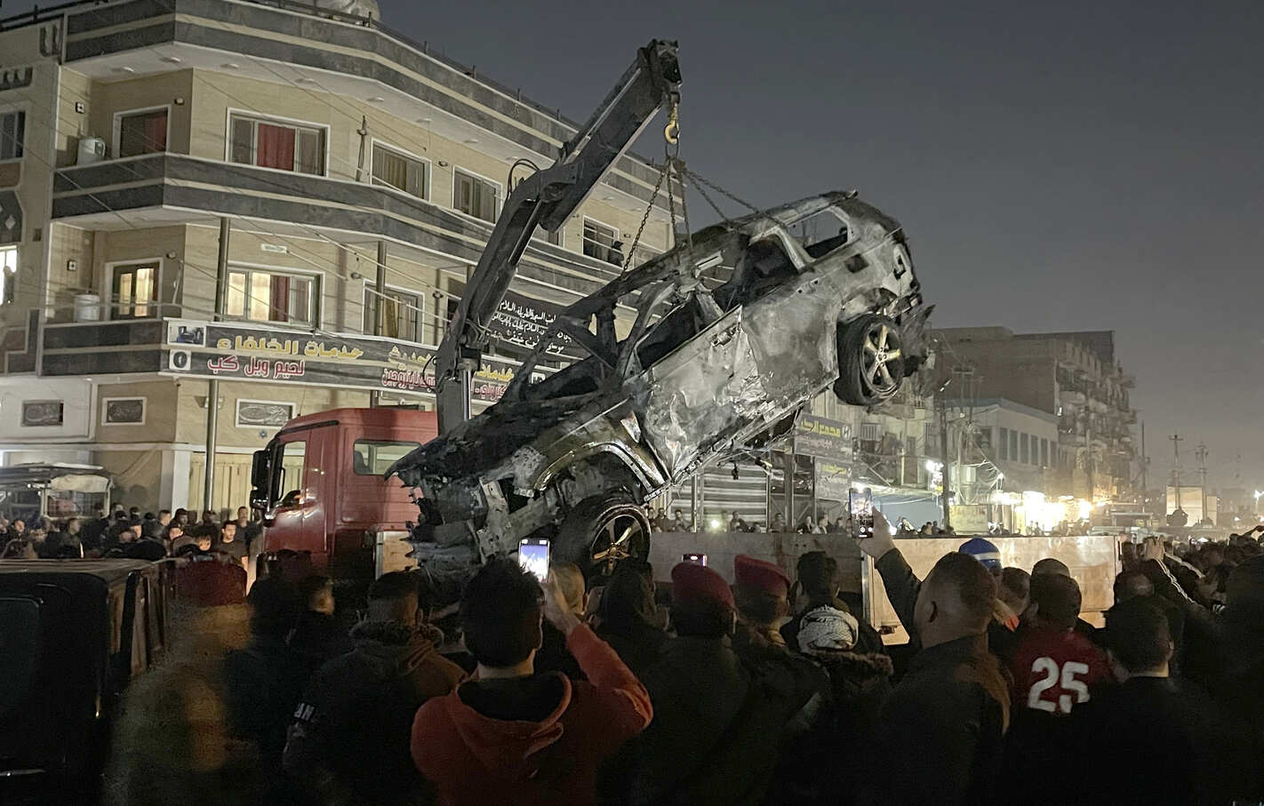 A crane lifts the wrecked car that has been targeted to kill the senior commander Abu Baqir al-Saadi of Popular Mobilization Forces (Al-Hashd al-Shaabi) in the eastern area of Al-Mashtal in Baghdad, Iraq, on February 7, 2024.