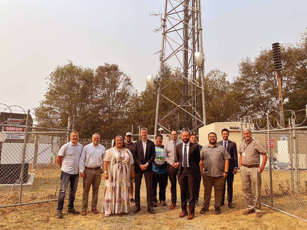 Federal and local representatives stand with tribal members in front of a new Internet tower built with a grant from the Biden administration’s Tribal Broadband Connectivity Program.