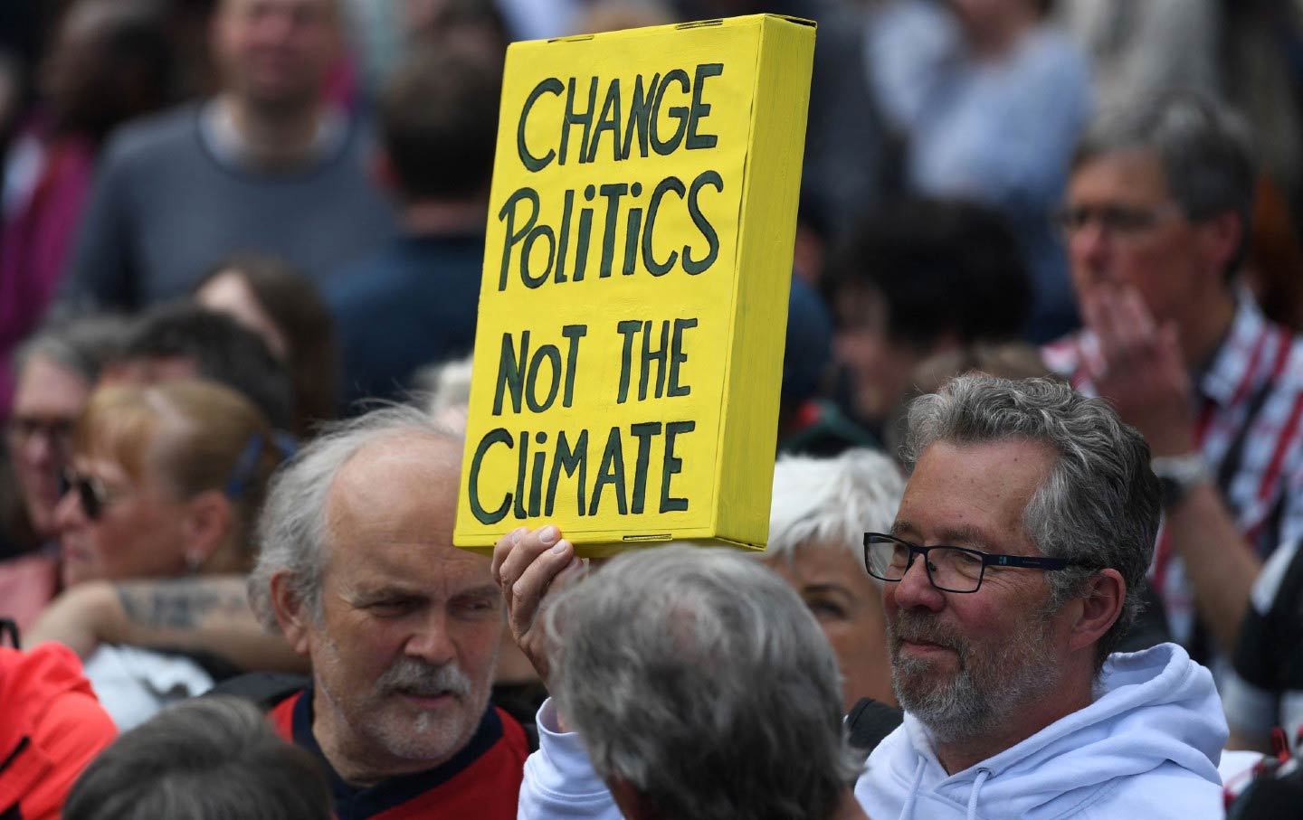 A man holds a placard reading "Change politics, not the climate" prior Germany's Social Democratic (SPD) party's final campaign meeting for the Bremen State elections in Bremen, northwestern Germany, on May 12, 2023.