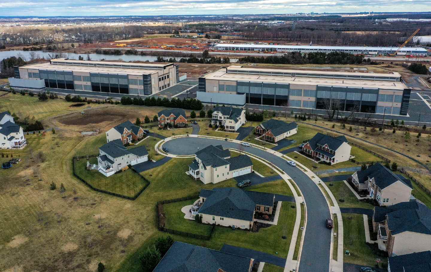 Amazon data centers loom over houses at the edge of the Loudoun Meadows neighborhood on January 20, 2023, in Aldie, Va. Microsoft is in the process of building data-center structures in the background.