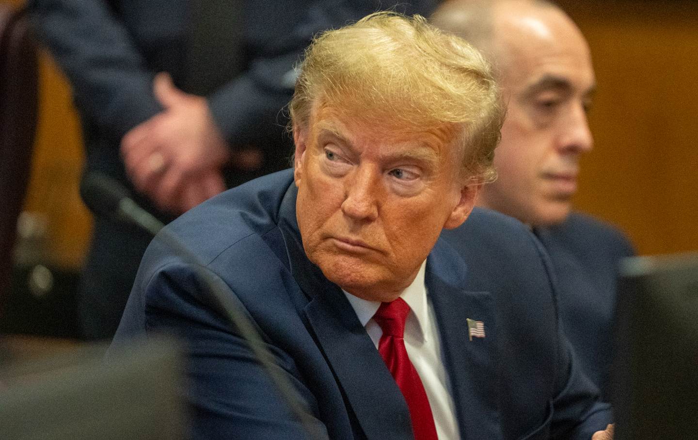 Donald Trump in a courtroom looking over his shoulder.