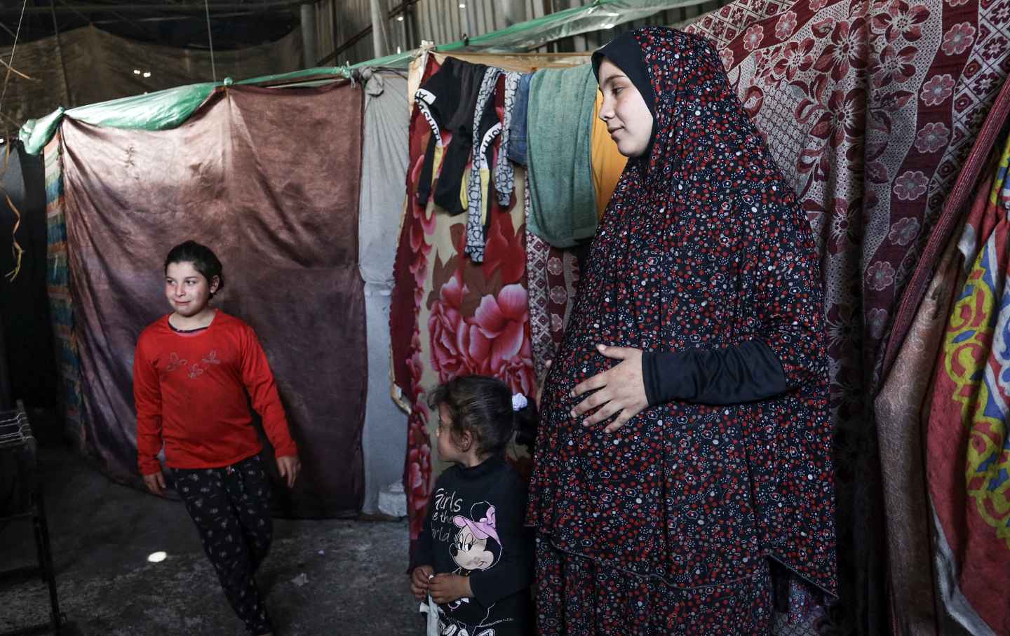 A pregnant Palestinian woman displaced from northern Gaza stands in a warehouse where she is taking shelter in Rafah, in the southern Gaza Strip, on February 29, 2024.