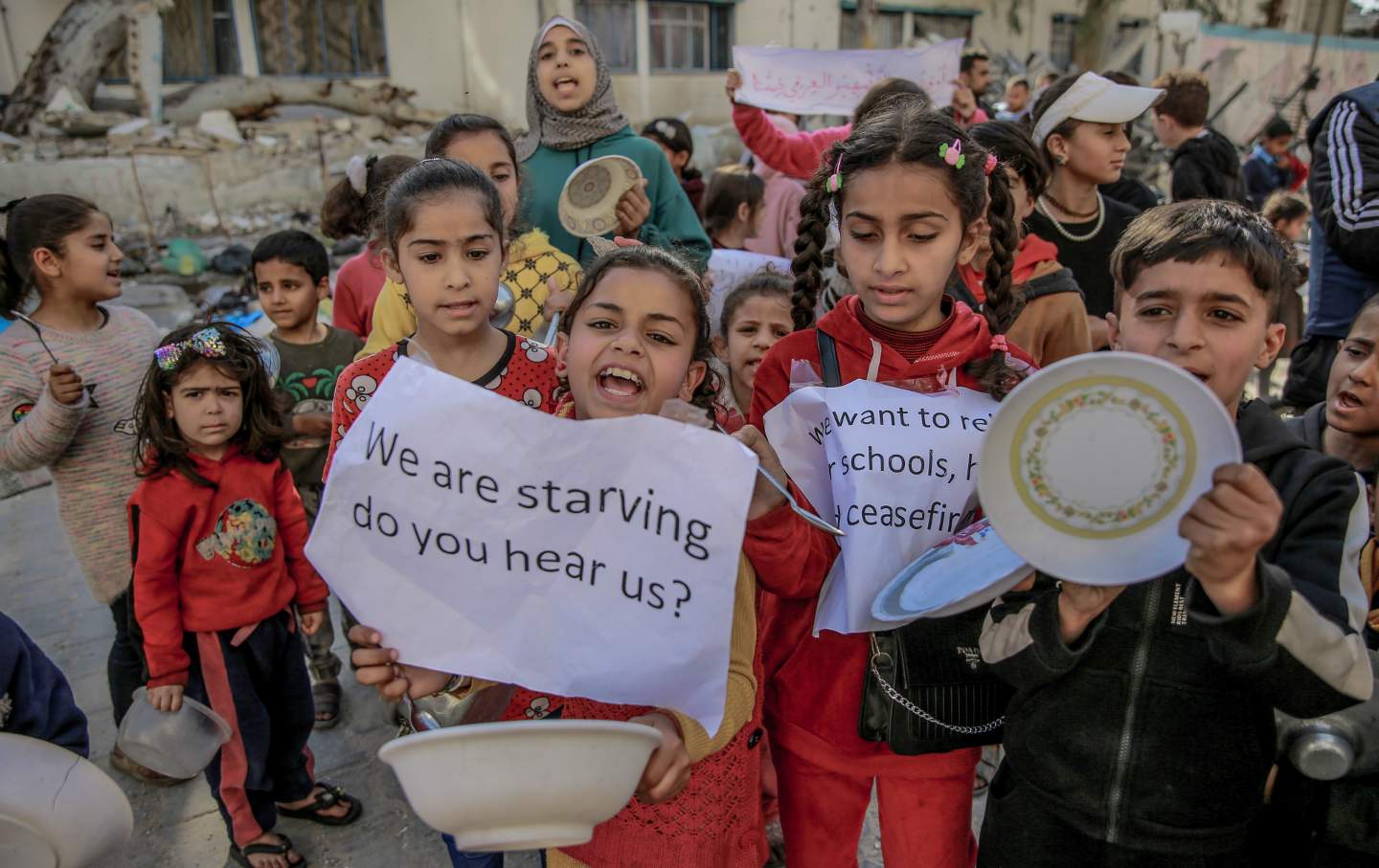 Palestinian children holding banners and empty bowls, gather to protest the food shortages in the city due to Israeli attacks and demanding a ceasefire in Gaza City, Gaza on March 12, 2024.