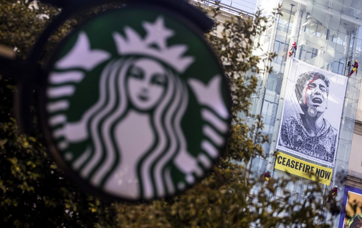 Pro-Palestine banners on a building with Starbucks logo in foreground