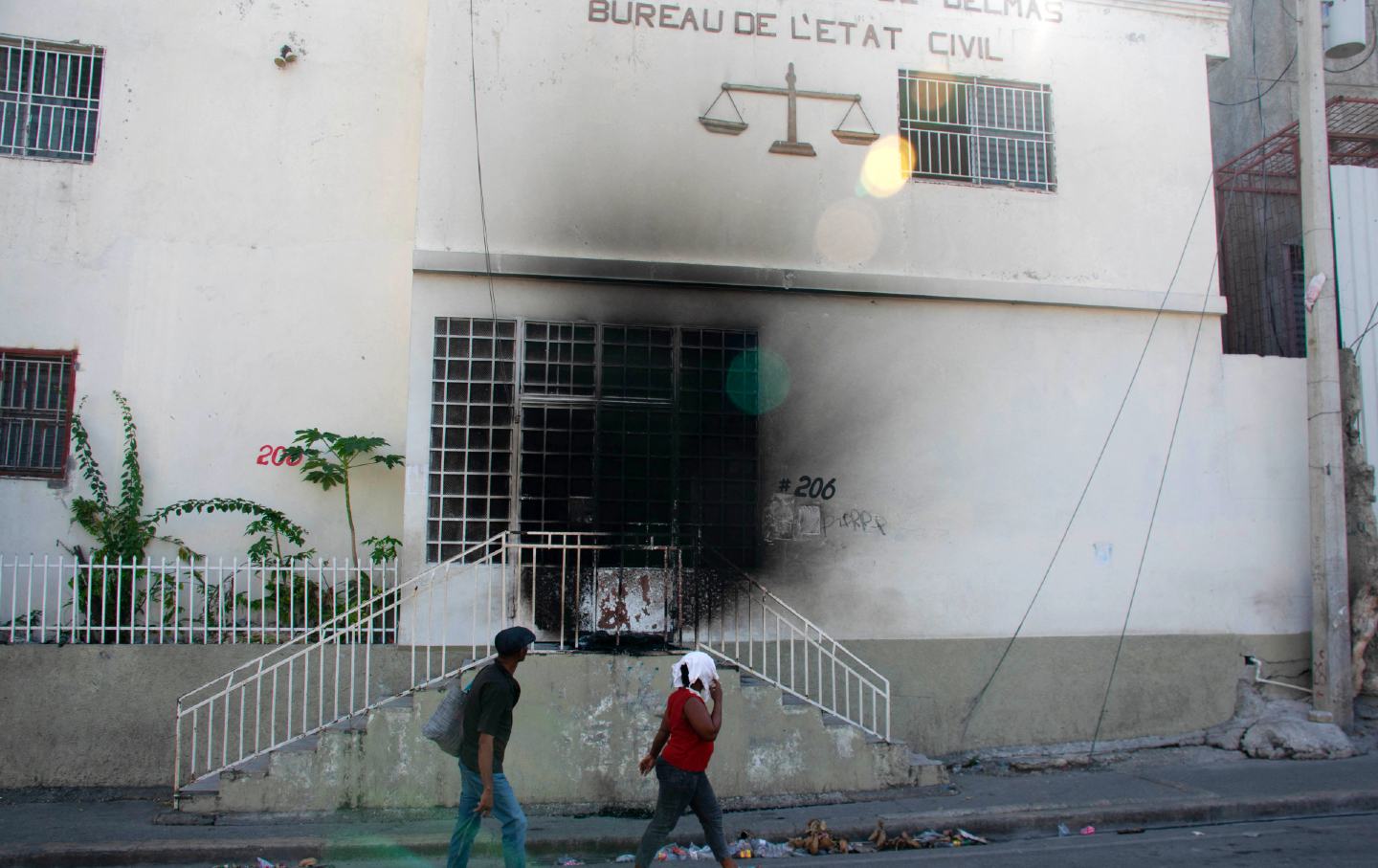 People walk by the tribunal set on fire the previous day by armed gangs in Port-au-Prince, Haiti, on March 6, 2024. Haiti’s capital was largely shut down on March 4, as authorities imposed a state of emergency after an attack on a prison freed thousands of inmates.