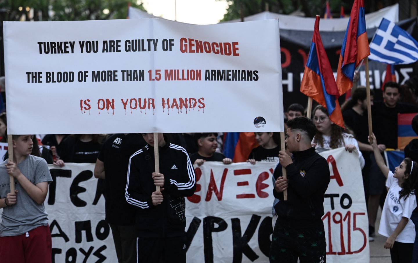 People hold flags and placards during a rally to commemorate the 109th anniversary of the Armenian genocide