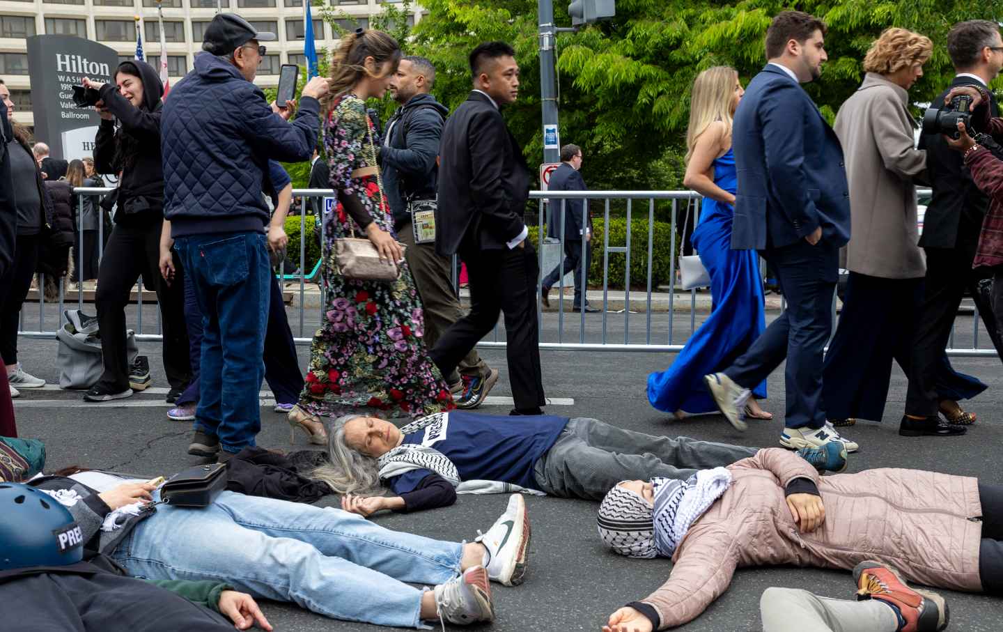 Members of the media and guests walk past protesters posing as slain Gaza journalists outside of the Washington Hilton ahead of the White House Correspondents' Dinner on April 27, 2024.