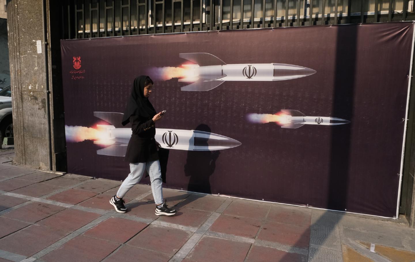 Woman walks by photo of Iranian missiles