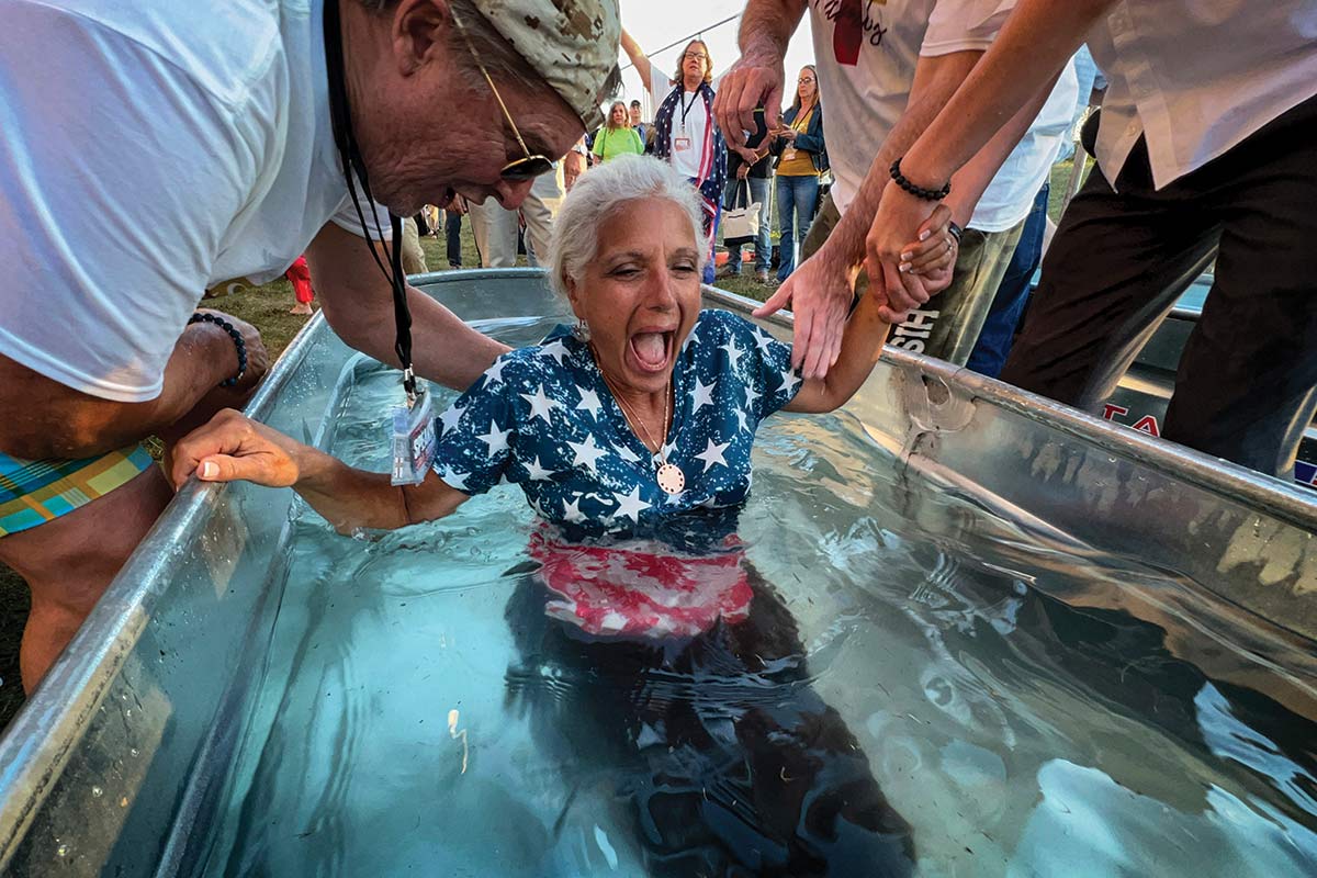A woman is baptized at a ReAwaken America event, which broadcasts the message that American Christianity is under siege.