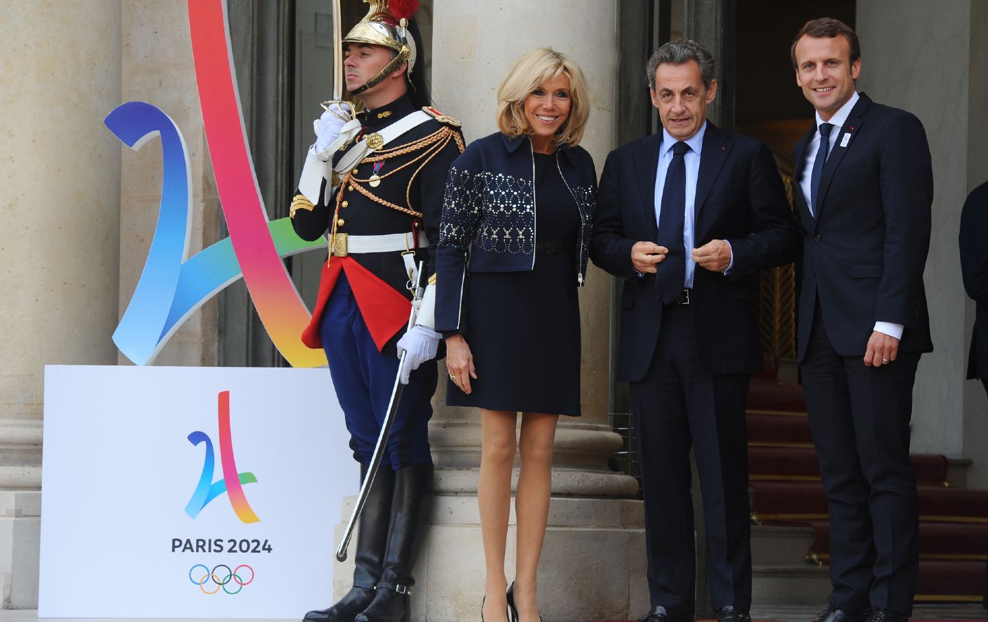 Macron and Sarkozy beside Olympics sign