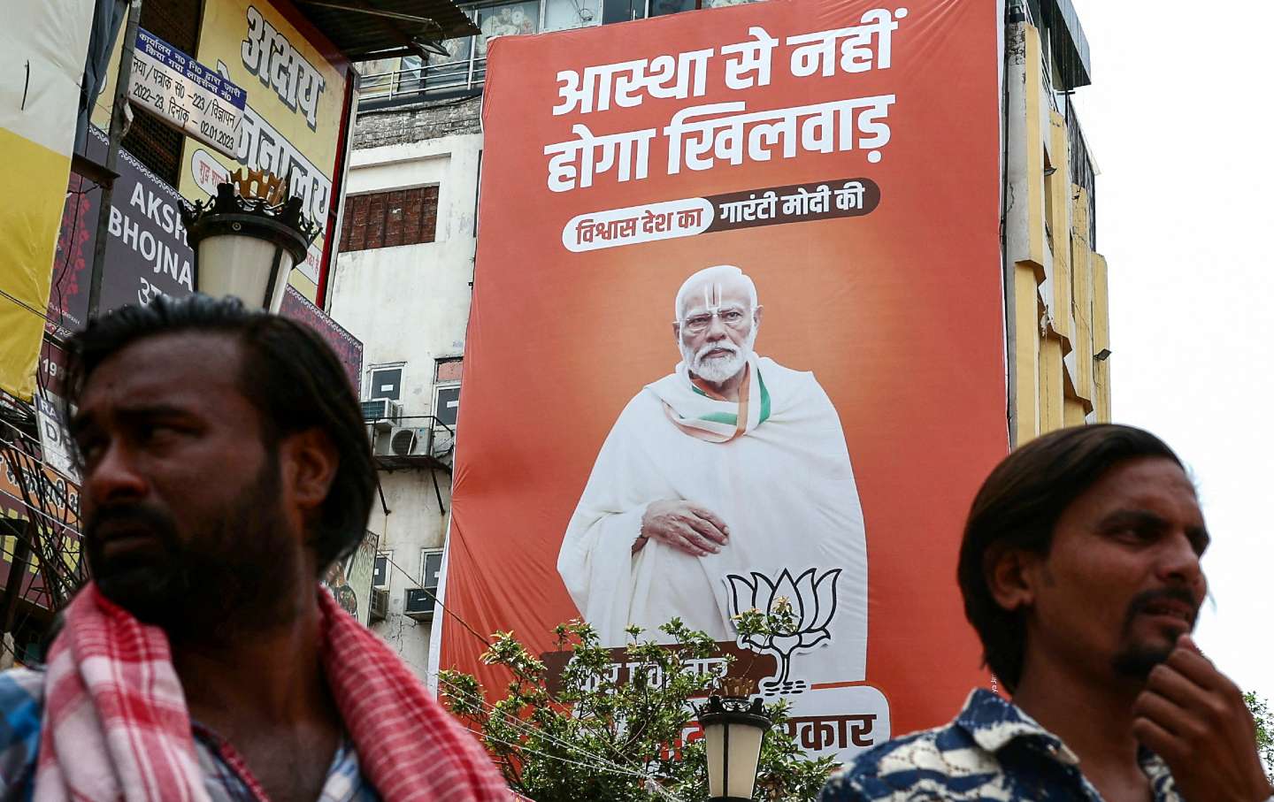 Men stand in front of an election campaign hoarding of the Bharatiya Janata Party featuring Indian Prime Minister Narendra Modi, in Varanasi on April 10, 2024, ahead of India's upcoming general elections.