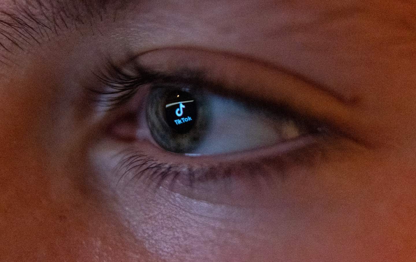 The TikTok social media platform's logo is reflected in the eye of a 13-year-old boy as he looks at a computer screen in Bath, England.