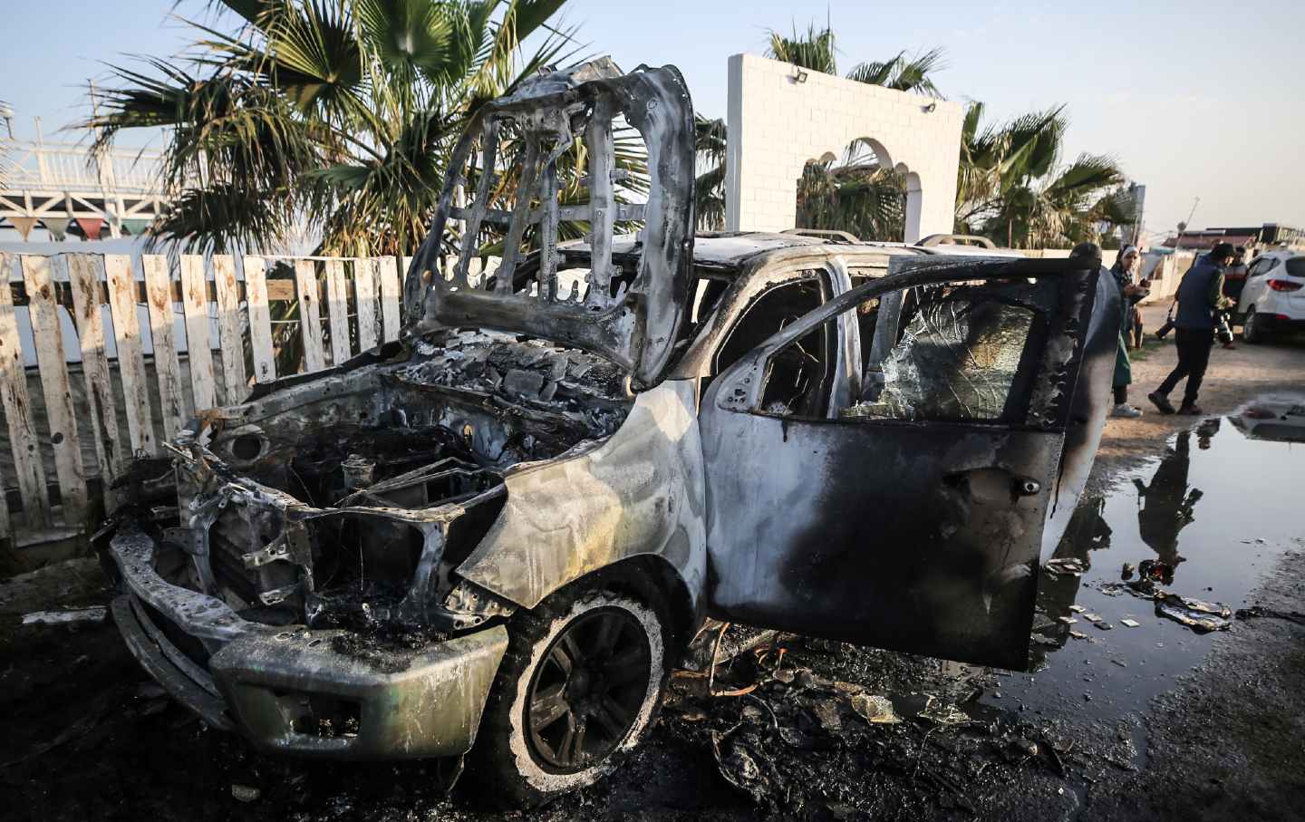 Palestinians standing next to a vehicle in the central Gaza Strip, where employees from the World Central Kitchen (WCK) were killed in an Israeli air strike.