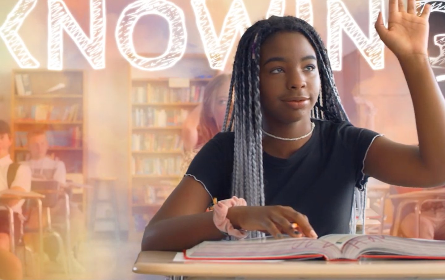 A still from an EducateUS ad, showing a Black teen raising her hand.