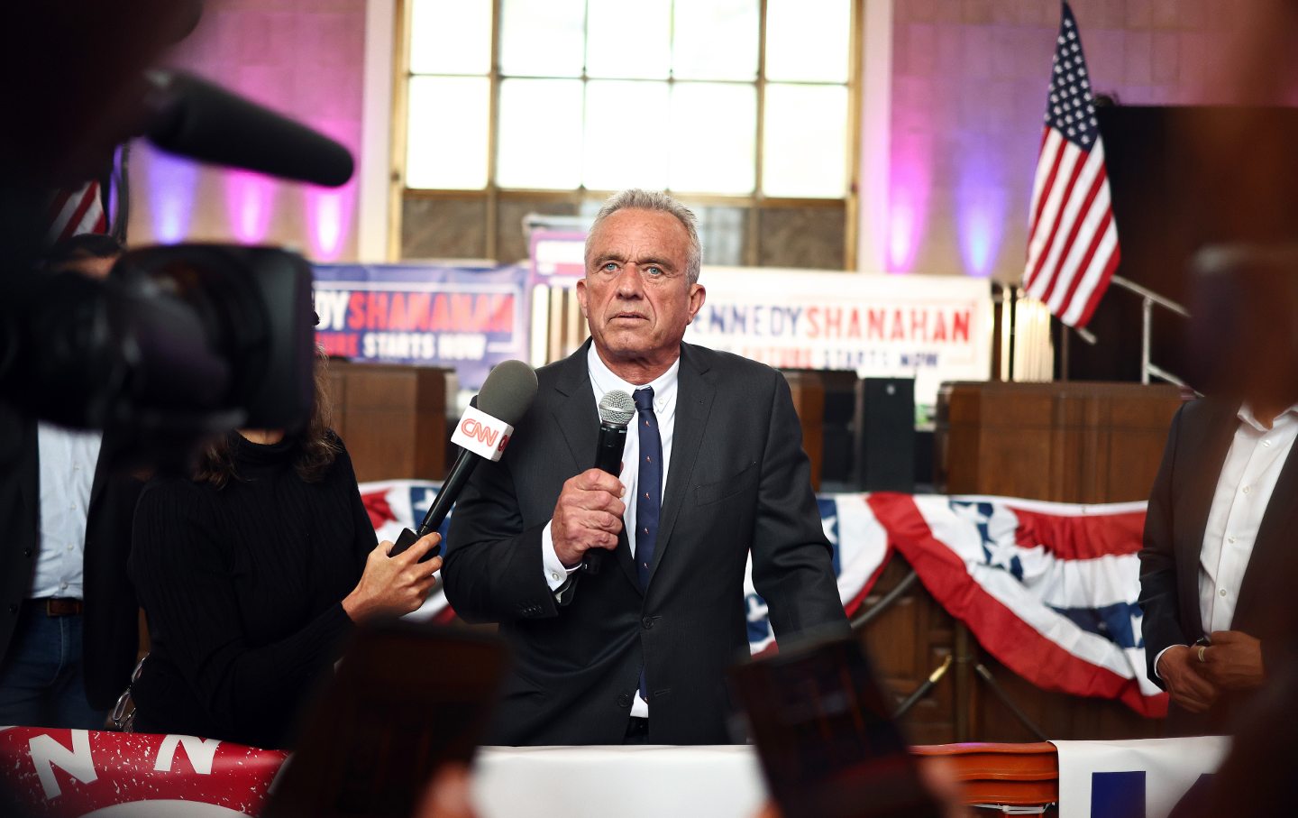 RFK Jr. at a podium holding a microphone.