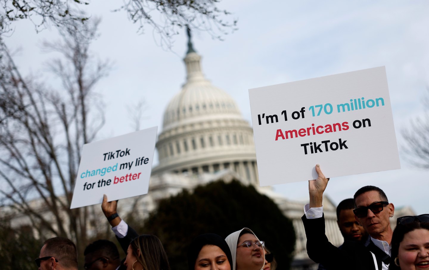 Proesters in front of the Capitol building with signs protesting the bill to force the sale of TikTok to an American-owned company. Signs read "I'm one of 170 million Americans on TikTok" and "TikTok changed my life for the better."