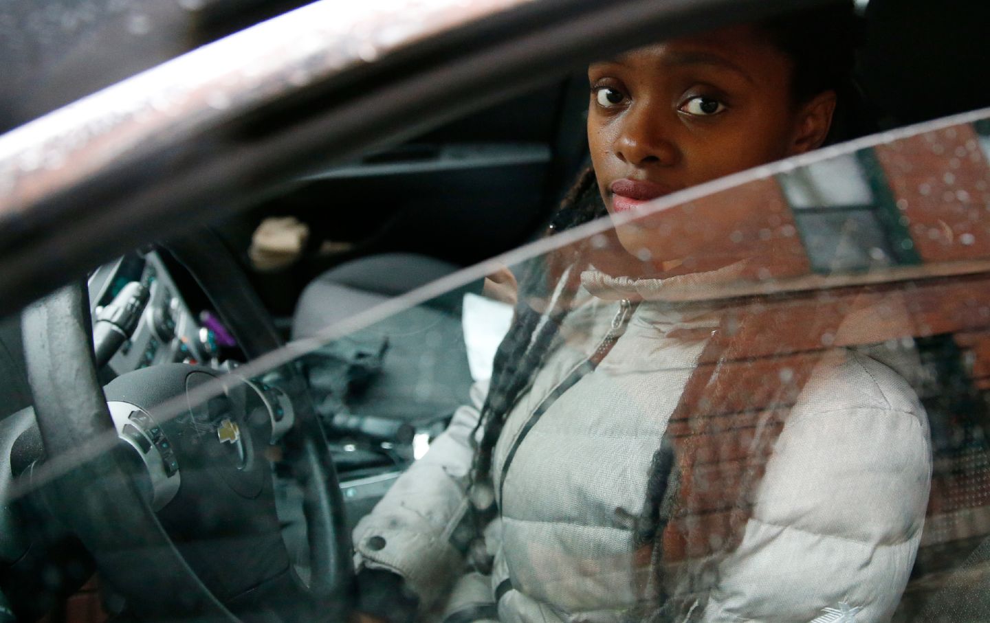 A woman sits in her car, which police had seized for a crime she did not commit.
