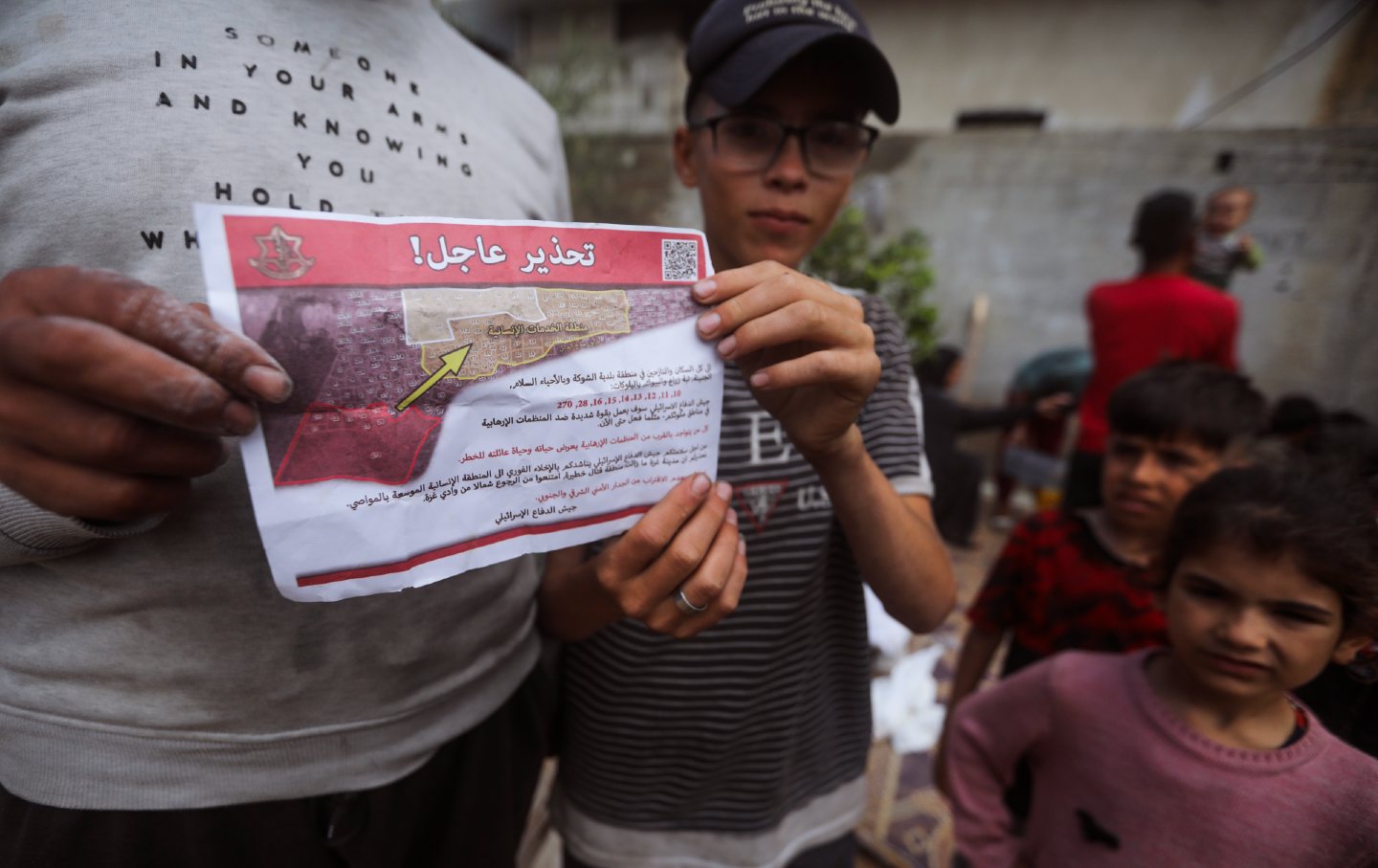 Palestinians hold leaflets dropped by Israeli planes calling on them to evacuate ahead of an Israeli military operation in Rafah, southern Gaza Strip, May 6, 2024.