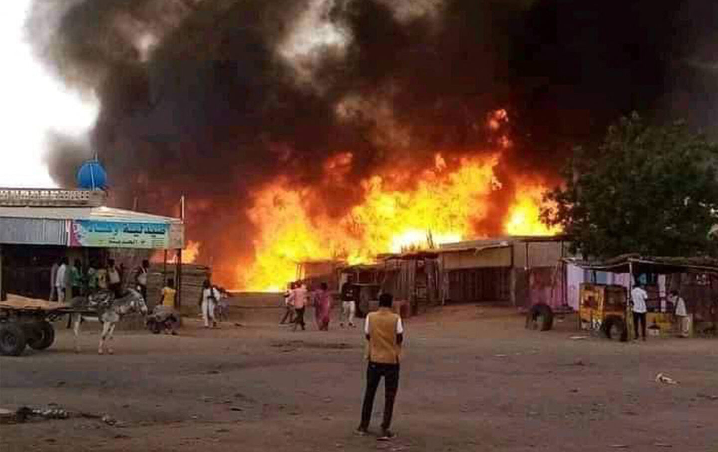 A man stands by as a fire rages in a livestock market area in al-Fasher, the capital of Sudan's North Darfur state, on September 1, 2023, in the aftermath of bombardment by the paramilitary Rapid Support Forces.