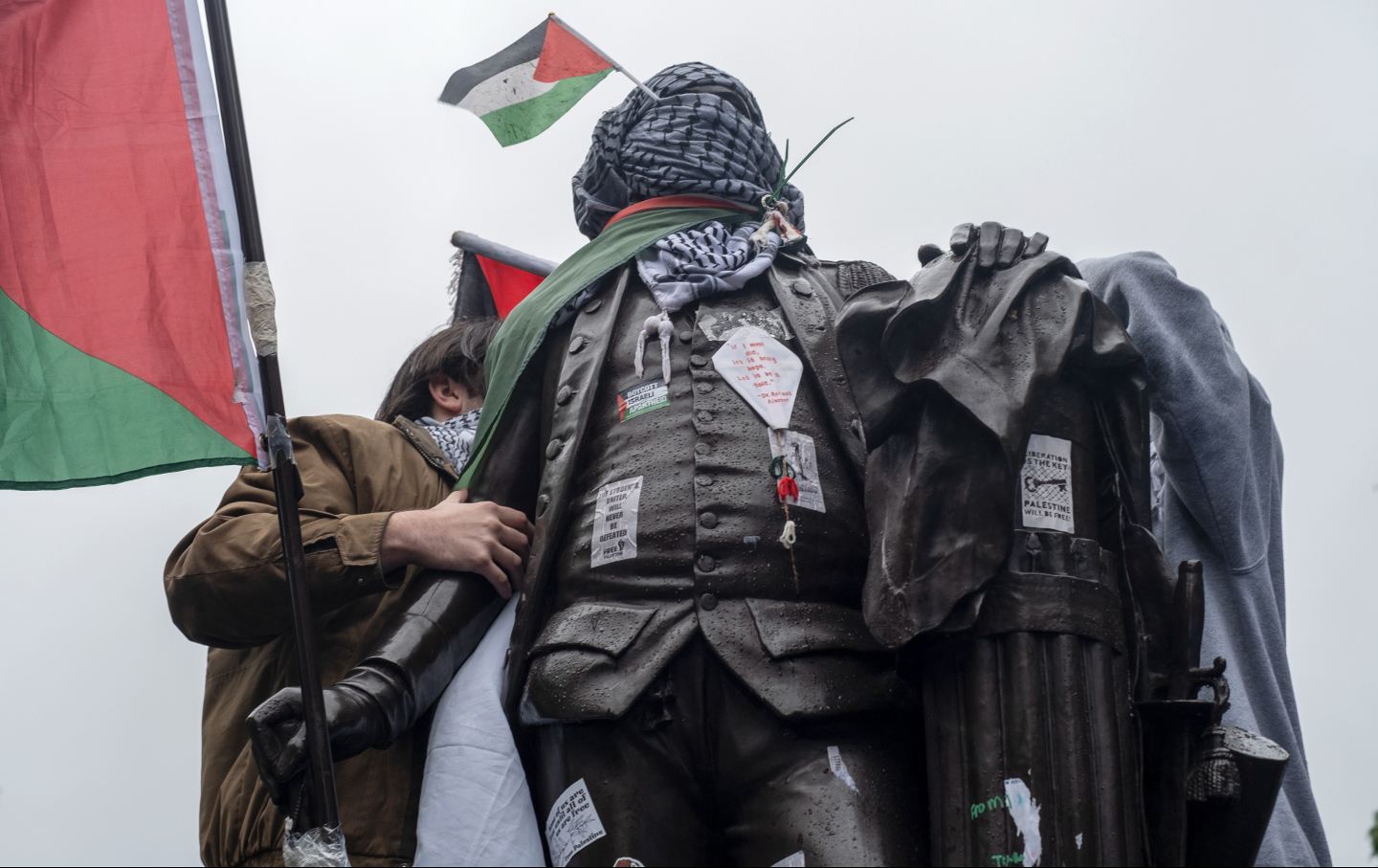 Students wrap Palestinian flag and Keffiye around the statue of George Washington at the George Washington University encampment protest.