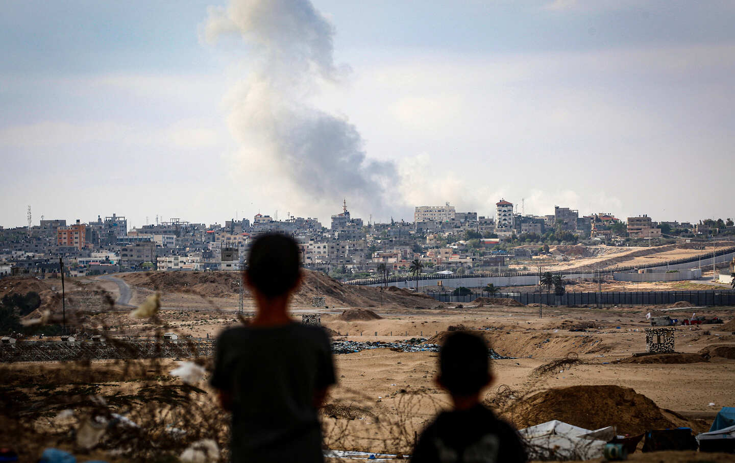 Boys watch smoke billowing during Israeli strikes east of Rafah in the southern Gaza Strip, on May 13, 2024.